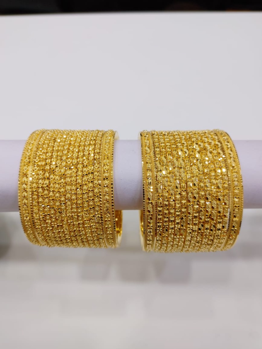 Two full stacks of patterned gold bangles on display at Shivani Jewellers