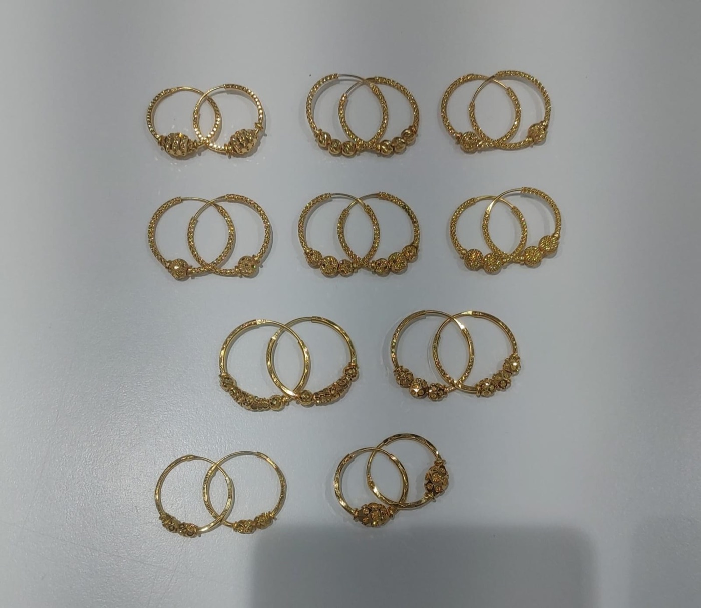 A selection of gold hoop earrings with beaded detailing at Shivani Jewellers