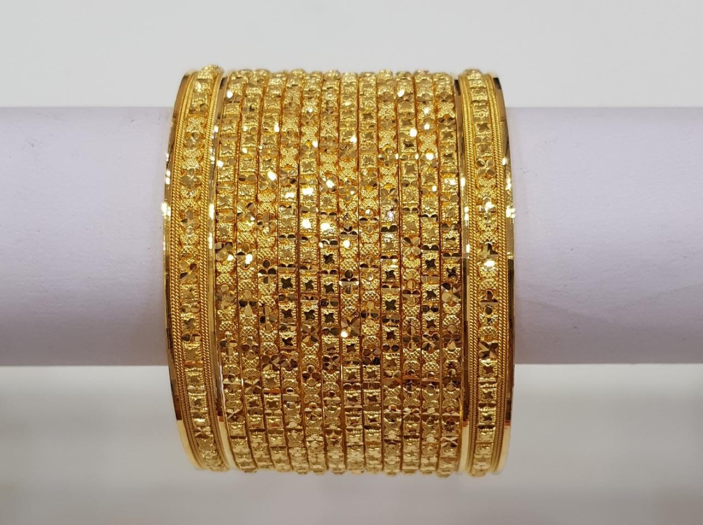A stack of intricately patterned gold bangles displayed at Shivani Jewellers